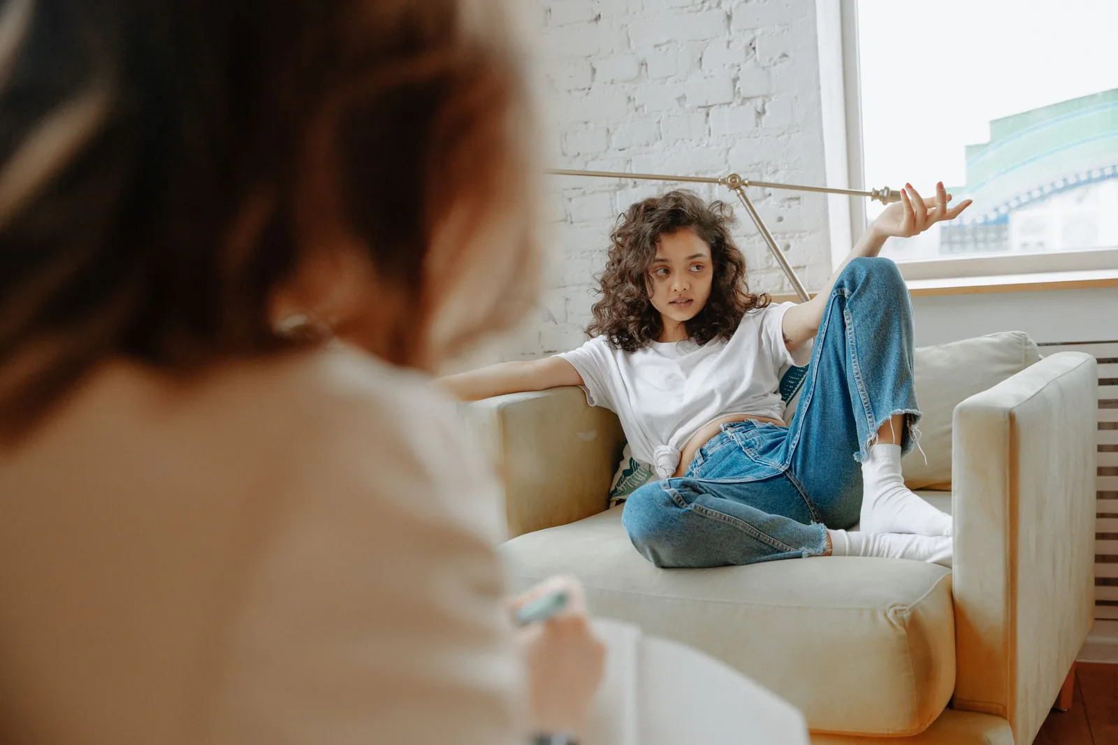 A teenager receiving counseling in a modern indoor setting, discussing mental health with a therapist
