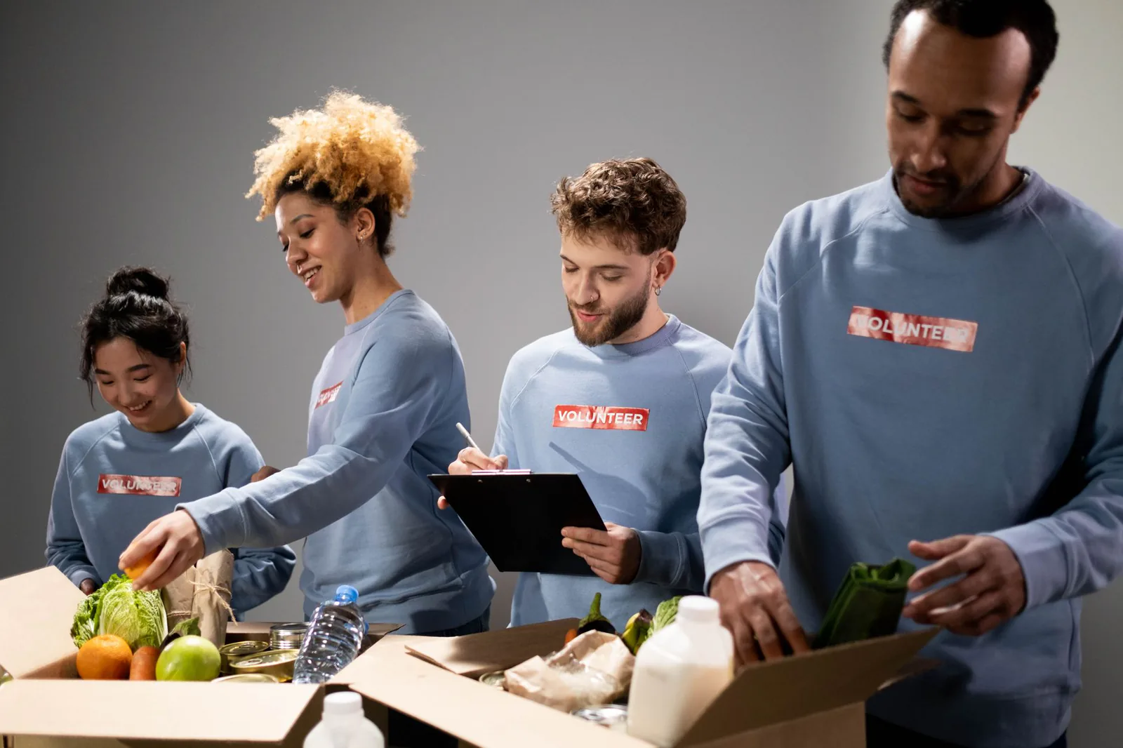 Four diverse volunteers packing food donations with teamwork and dedication